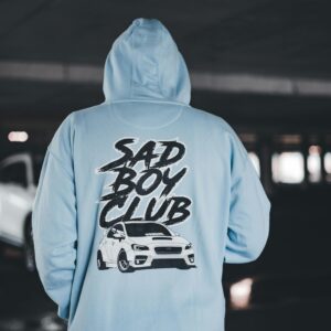 Person in Blue Hoodie with Sad Boy Club Script in Garage